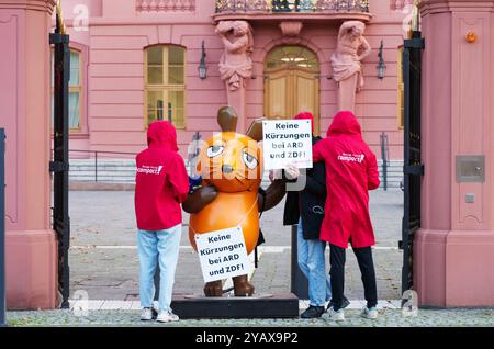 16. Oktober 2024, Rheinland-Pfalz, Mainz: Die Figur der Maus aus der Sendung mit der Maus steht zwischen Aktivisten der Kampagne vor dem Rheinland-pfälzischen landtag mit Schildern mit der Aufschrift „keine Kürzungen an ARD und ZDF!“. Aktivistinnen und Aktivistinnen des „Campact e.V.“ sind mit der entführten „Maus“ vor dem ZDF und dem landtag in der Landeshauptstadt erschienen. Die Aktivisten wollen die Aufmerksamkeit auf den Wert des öffentlich-rechtlichen Rundfunks lenken. Jahrelang schmückte die Skulptur der Kultfigur aus der Sendung mit der Maus das vierteilige Gebäude des Westdeutschen Rundfunks (WDR) in Köln Stockfoto