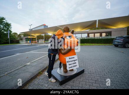 16. Oktober 2024, Rheinland-Pfalz, Mainz: Die Figur der Maus aus Sendung mit der Maus trägt ein Schild mit der Aufschrift „keine Kürzungen an ARD und ZDF!“ Um den Hals hängt daneben ein Aktivist von Campact im Eingangsbereich zum ZDF. Aktivistinnen und Aktivistinnen des „Campact e.V.“ sind mit der entführten „Maus“ vor dem ZDF und dem landtag in der Landeshauptstadt erschienen. Die Aktivisten wollen die Aufmerksamkeit auf den Wert des öffentlich-rechtlichen Rundfunks lenken. Jahrelang schmückte eine Skulptur der Kultfigur aus der Sendung mit der Maus das vierteilige Gebäude des Westdeutschen Rundfunks (WDR) in Köln Stockfoto