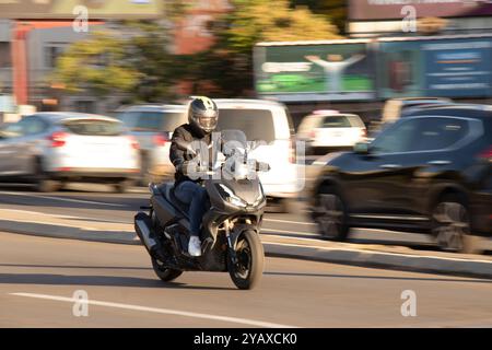 Belgrad, Serbien - 10. Oktober 2024: Junger Motorradfahrer, der an einem sonnigen Tag auf einer belebten Stadtstraße fährt Stockfoto