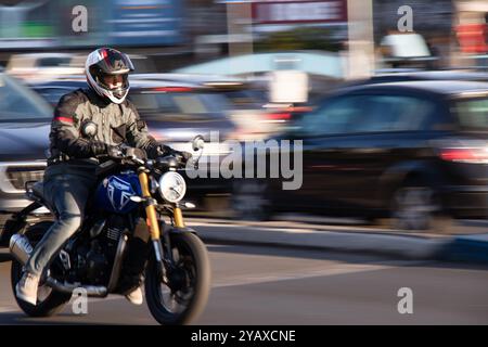 Belgrad, Serbien - 10. Oktober 2024: Junger Motorradfahrer, der an einem sonnigen Tag auf einer belebten Stadtstraße fährt Stockfoto