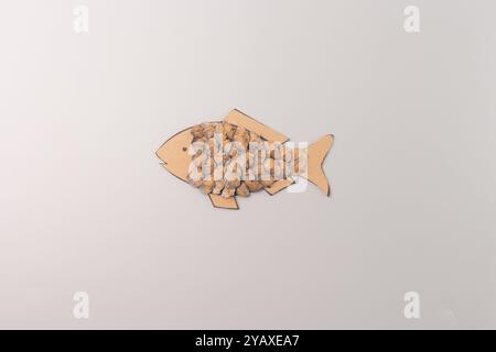 Natürliche Materialien für Kinder Kreativität, Fischfigur aus Tannenzapfen Samenschalen, Draufsicht, grauer Hintergrund, Schritt im kreativen Prozess, DIY, Inst Stockfoto