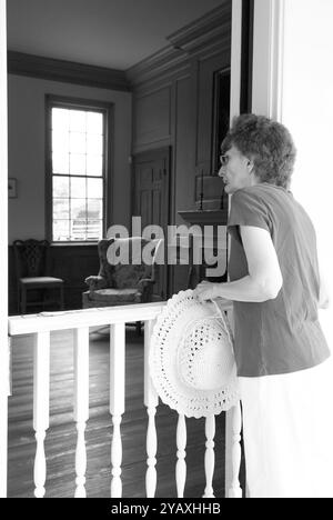 Eine ältere Frau, 55 bis 60 Jahre alt, die sich eine historische Ausstellung in einem alten Haus im Revolutionary war Park in Camden, South Carolina, USA ansieht. Stockfoto