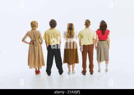 Eine Gruppe von fünf Personen steht in einer Linie, mit dem Rücken zur Kamera hin, wodurch ein Gefühl der Vorfreude entsteht, wenn sie etwas gemeinsam beobachten. Stockfoto