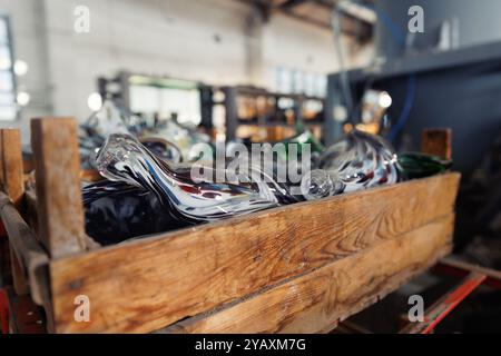 Viele bunte Glasvasen in Holzkiste in der Glasbläserei Fabrik mit Ofenausrüstung auf Hintergrund gesetzt. Handgefertigtes Blasen Stockfoto