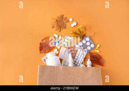 Einkaufstasche mit verschiedenen Apothekenmedikamenten, Kapseln und Pillen mit Herbstblättern auf braunem Herbsthintergrund. Saisonale Herbstmedikamente, Erkältung Stockfoto