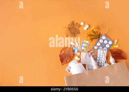 Einkaufstasche mit verschiedenen Apothekenmedikamenten, Kapseln und Pillen mit Herbstblättern auf braunem Herbsthintergrund. Saisonale Herbstmedikamente, Erkältung Stockfoto