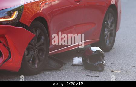 Hamburg, Deutschland. Oktober 2024. Der Helm eines Motorradfahrers, der an einem Unfall beteiligt war, liegt neben einem Unfallfahrzeug auf der Helgoländer Allee. Aus noch ungeklärten Gründen kollidierte ein Motorradfahrer auf der Helgoländer Allee mit einem Autofahrer. Das Motorrad wurde auf den Bürgersteig geworfen und landete Meter entfernt auf einer Mülltonne. Ein Notarzt musste sich um den verletzten Motorradfahrer kümmern. Quelle: Marcus Brandt/dpa/Alamy Live News Stockfoto