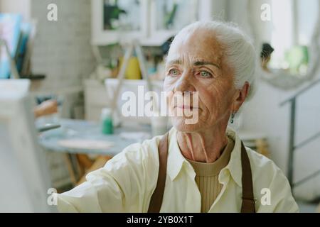 Mittlere Nahaufnahme des weiblichen Gesichts mit Falten und hellem Make-up, sie blickte mit ihren eisblauen Augen auf Leinwand Stockfoto