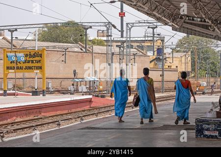 Drei Reisende spazieren am Hauptbahnhof Madurai, Tamil Nadu, auf einen Bahnsteig, der auf die Ankunft eines Zuges wartet Stockfoto