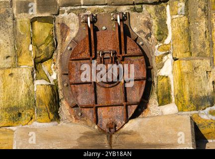 Ein alter korrodierter strom-Abfluss in der Ufermauer auf Scarborough Foreshore. Diese alten Regenwasserabflüsse leiten immer noch das Abwasser aus der Stadt direkt von mir ab Stockfoto