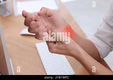 Mann mit Schmerzen im Handgelenk am Tisch, Nahaufnahme. Büroarbeit, Karpaltunnelsyndrom Stockfoto