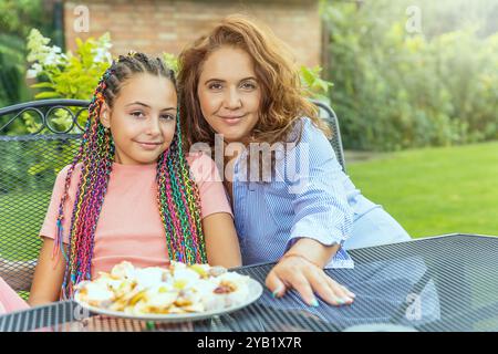 Porträt von langhaarigen Mutter und Tochter sitzen mit Käse am Tisch. Außen. Horizontal. Stockfoto