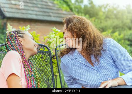 Porträt von Mutter und Tochter, die sich am Gartentisch anschauen. Horizontal. Stockfoto