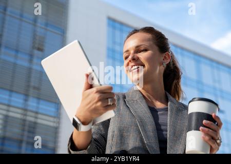 Geschäftsfrau, die ihr digitales Tablet vor dem Hintergrund eines Unternehmens oder Gebäudes verwendet. Cybersicherheit, E-Commerce, KI-Technologie, Elektronikindustrie. Stockfoto