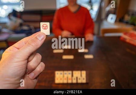 Das klassische Brettspiel rummikub zu Hause spielt, die Hand hält einen Scherzstein Stockfoto