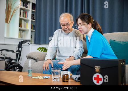 Asiatische Krankenschwester in weißer Uniform mit Stethoskop Besuch nach Hause und hilft, älteren Mann Patienten zu konsultieren Stockfoto
