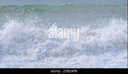 Das Meer ist rau und die Wellen stürzen gegen das Ufer. Der Himmel ist bewölkt und das Wasser hat eine tiefblaue Farbe Stockfoto