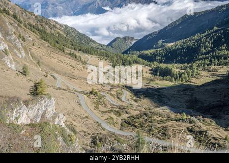 Landschaft mit Haarnadelrurnen der gewundenen Straße auf der nördlichen Seite des Passes und niedrigen Wolken im Susa-Tal, aufgenommen im hellen Herbstlicht vom Finestre Pass, Tor Stockfoto