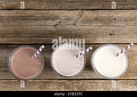 Verschiedene leckere Proteincocktails in Gläsern auf Holztisch, flach gelegt. Leerzeichen für Text Stockfoto