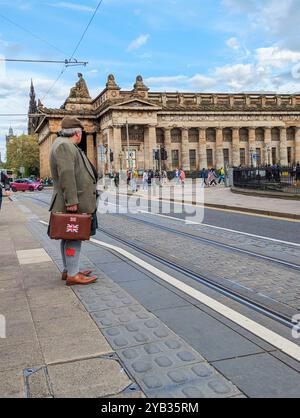 Edinburgh, Schottland, 10. Mai 2024: Ein Schotte in traditionellen Uniformen aus Kilts und Sportlern wartet auf eine Straßenbahn in der Princess Street. Stockfoto