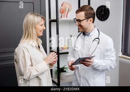 Männlicher Arzt, der einen Aerosolinhalator in der Hand hält, bei einer Demonstration einer Patientin in seiner Praxis. Stockfoto