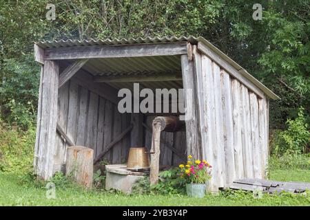 Ein alter Holzschuppen, unter dem sich ein Brunnen mit Eimern befindet Stockfoto