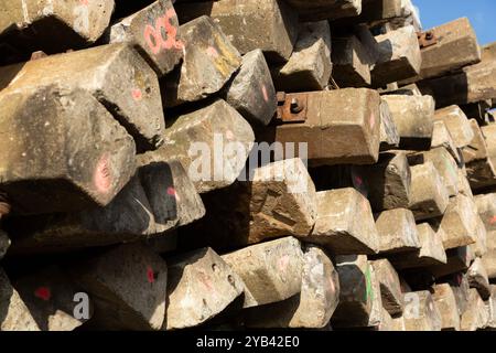 Nahaufnahme eines Stapels sortierter hölzerner Bahnschwellen mit Schrauben und Halterungen. Stockfoto