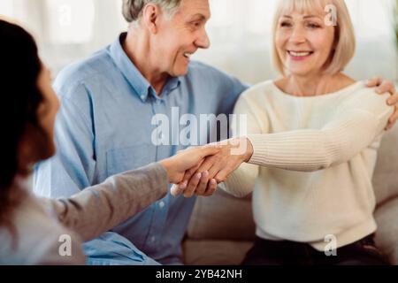 Glückliches, reifes Paar, das dem Arzt im Büro einen Handschlag gibt Stockfoto