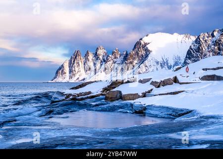 Tungeneset oder Devils Jaw Mountain auf Senja Island, Norwegen im Winter. Winterlandschaft mit schneebedeckten Berggipfeln, Fjordgewässern und Eisküste Stockfoto