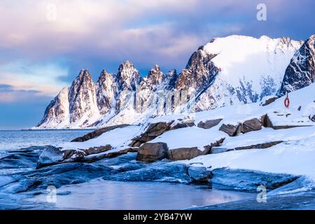 Tungeneset oder Devils Jaw Mountain auf Senja Island, Norwegen im Winter. Winterlandschaft mit schneebedeckten Berggipfeln, Fjordgewässern und Eisküste Stockfoto