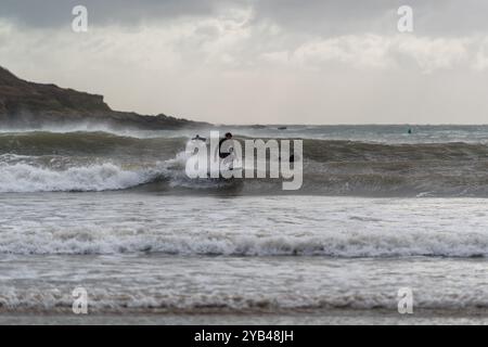 Surfer können Storm Brian optimal nutzen, indem sie in Salcombe, South Hams, Devon, die Wellen auf den North Sands ziehen und für die Herbsttemperaturen volle Weste tragen. Stockfoto