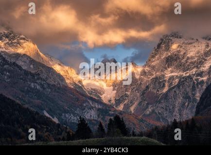 Sonnendurchflutete, schneebedeckte Berggipfel leuchten unter dramatischen Wolken Stockfoto