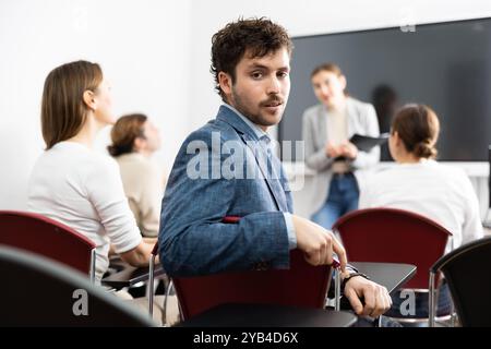 Porträt eines erfolgreichen jungen Mannes, der an Sprachkursen mit einer Gruppe von Menschen im Klassenzimmer teilnimmt Stockfoto