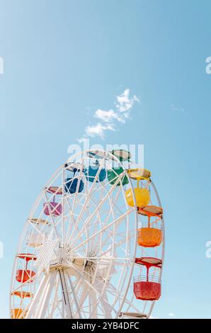Farbenfrohes Riesenrad, das an einem sonnigen Tag in Tibidabo in Barcelona vor einem hellblauen Himmel mit weichen Wolken steht Stockfoto
