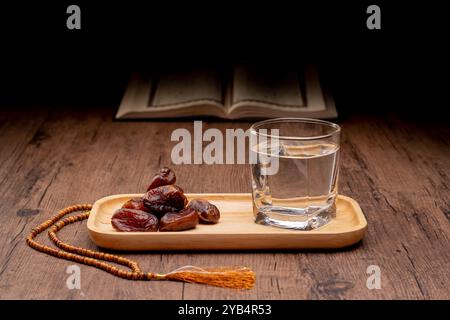 Viele Dattelpalmen stehen auf Schüsseln und Tassen Wasser und der Koran steht auf Holztischen, um auf die Zeit des Iftar zu warten, mit dem Konzept der ramadan Muslime A Stockfoto