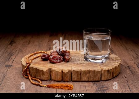 Viele Dattelpalmen stehen auf Schüsseln und Tassen Wasser und der Koran steht auf Holztischen, um auf die Zeit des Iftar zu warten, mit dem Konzept der ramadan Muslime A Stockfoto