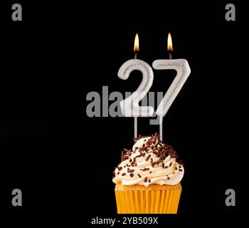 Geburtstagskuchen auf schwarzem Hintergrund - Zahl 27 geformte Kerzen. Stockfoto