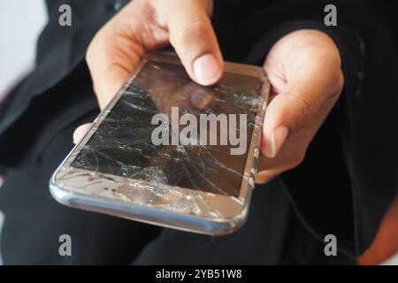 Nahaufnahme einer Frau, die ein kaputtes Smartphone hält. Stockfoto