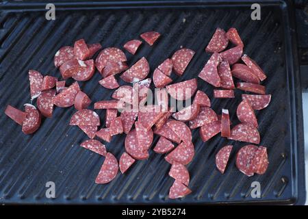 Gegrillte Salamischeiben, die wunderschön auf der Kochfläche angeordnet sind, sorgen für einen herzhaften Genuss Stockfoto