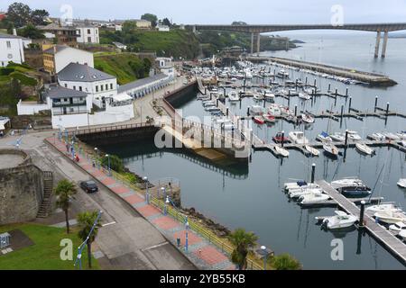 Blick auf einen Hafen mit zahlreichen Booten, umliegende Architektur und eine Brücke im Hintergrund an einem bewölkten Tag, Ribadeo, Fluss EO, Galicien, Spanien, Eur Stockfoto