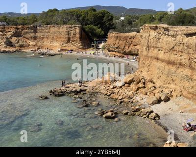 Kleiner Strand mit klarem Wasser, umgeben von hohen Klippen und Felsen in Playa es Bol Nou, Sa Caleta, Ibiza, Balearen, Spanien, Europa Stockfoto