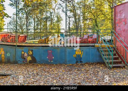 Ein alter, rostiger, verlassener Vergnügungspark. Eine verblasste Karnevalsfahrt mit Cartoon-Graffiti in einem verfallenen Zustand. Stockfoto