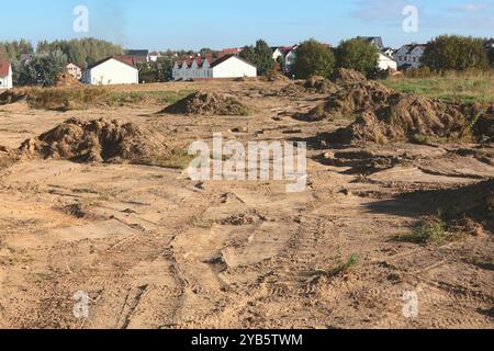 Bodenbelag für den Bau neuer Wohngegenstände. Grundstückshaufen auf der Baustelle vor dem Hintergrund von gebauten Häusern. Gebäude und Stockfoto
