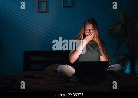 Schockierte überraschte Frau mit Brille, die nachts mit Laptop Filme anschaute. Technologie, Internet, Kommunikation und Menschenkonzept Stockfoto