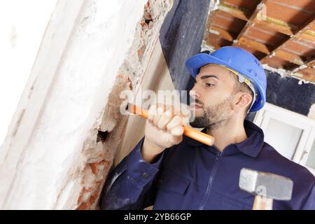 baumeister pflückt mit Hammer und Meißel um Stein Stockfoto