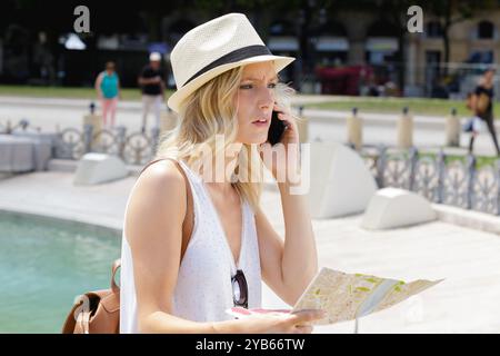 Glückliche Frau, die am Telefon nach dem Weg fragt Stockfoto