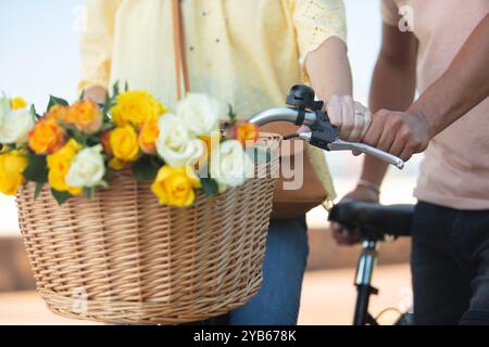 Frauen, die Fahrrad fahren, mit Blumenstrauß im Korb Stockfoto