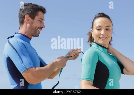 Männliche und weibliche Surfer ziehen Taucheranzug an Stockfoto
