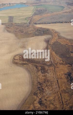 Im Spätherbst über die Landschaft fliegen. Aus der Vogelperspektive auf das ländliche Gebiet mit Feldern, Wiesen und Seen. Stockfoto