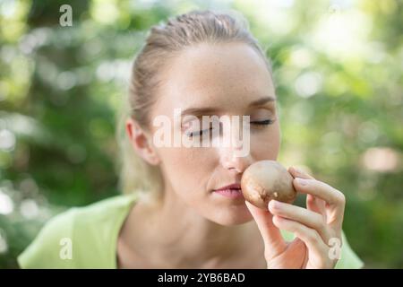 Frau im Wald, die einen wilden Pilz riecht Stockfoto